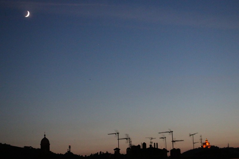 Nighttime skyline of Bologna with the Church that has an icon painted by St.Luke lit up in the distance.